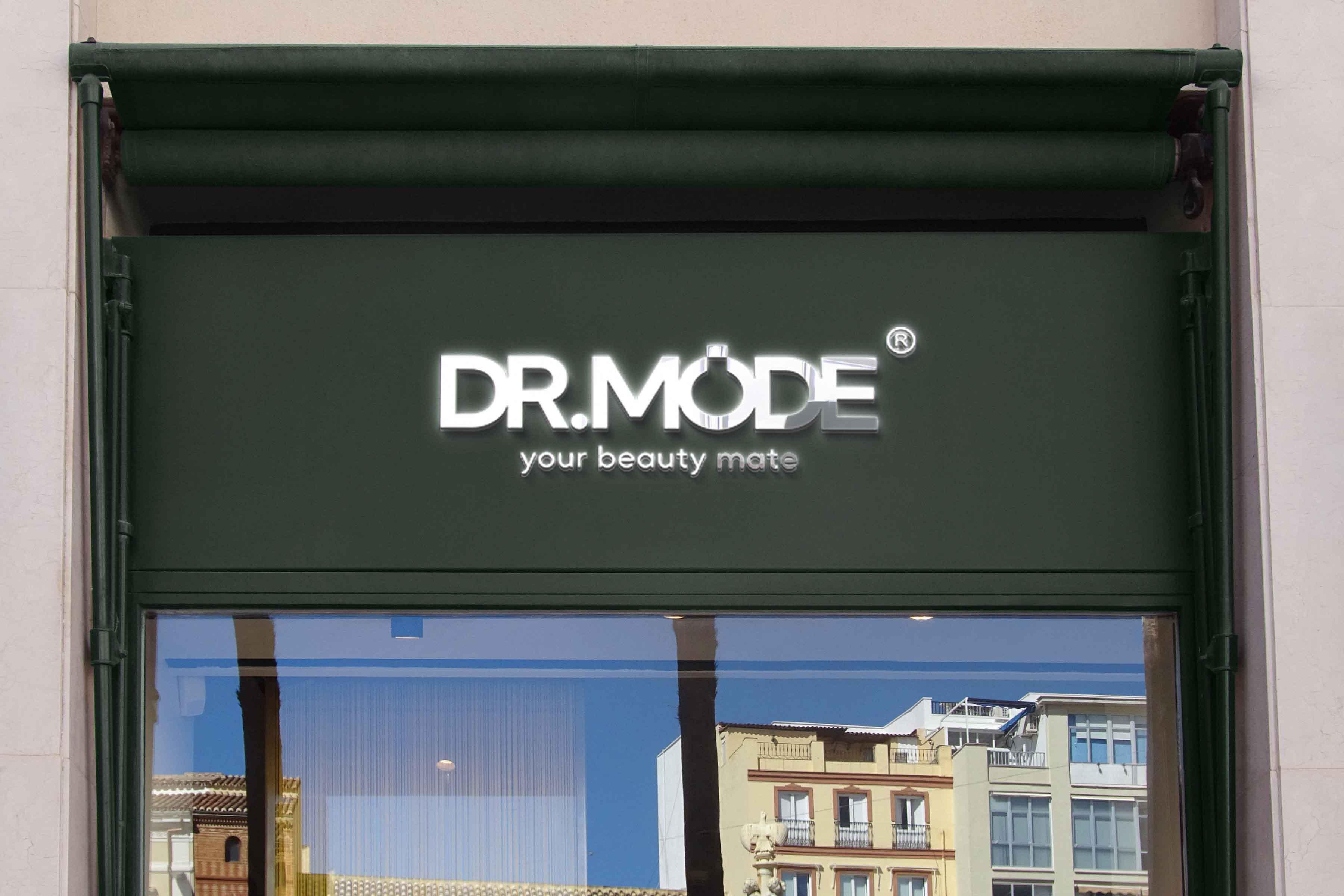 Storefront with illuminated 'DR.MODE your beauty mate' sign on green exterior, city buildings reflected in glass